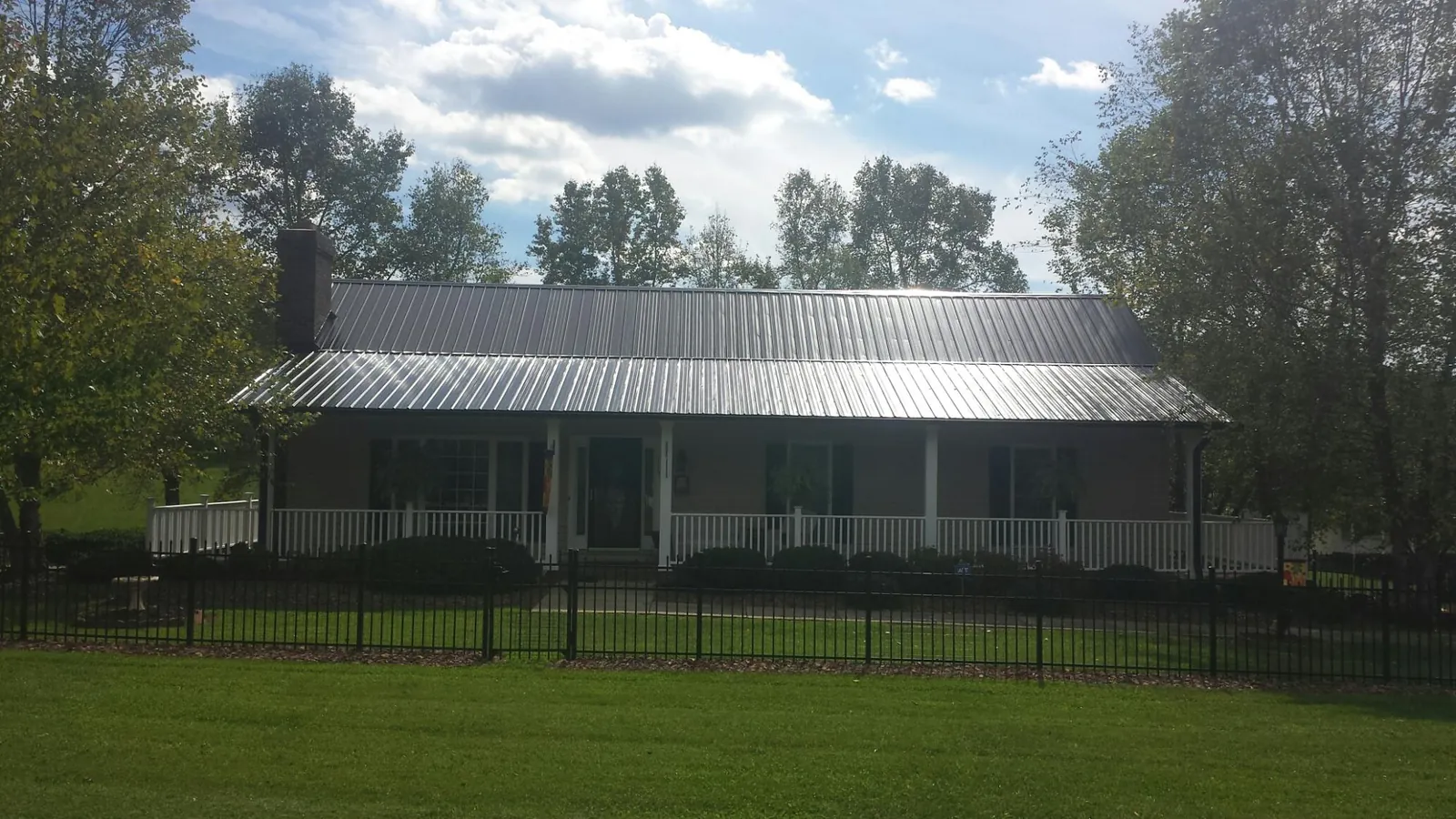 Gray metal roof on a brick ranch with a full width front porch — Gutter Guard Installation work by our crew in Walnut Grove